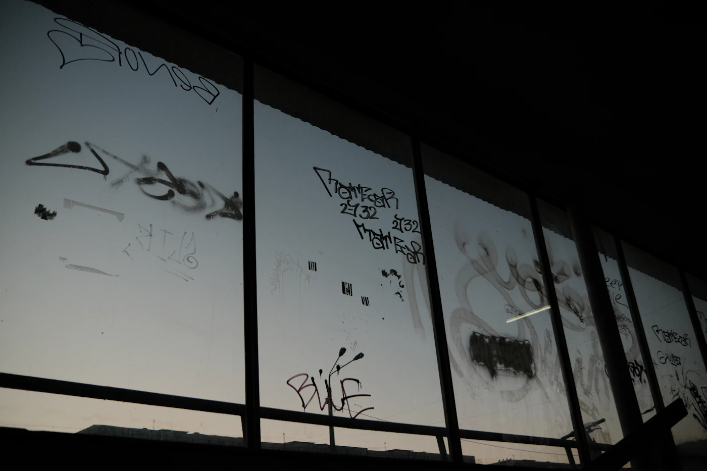Graffiti tags scrawled across a large pane of street-level glass