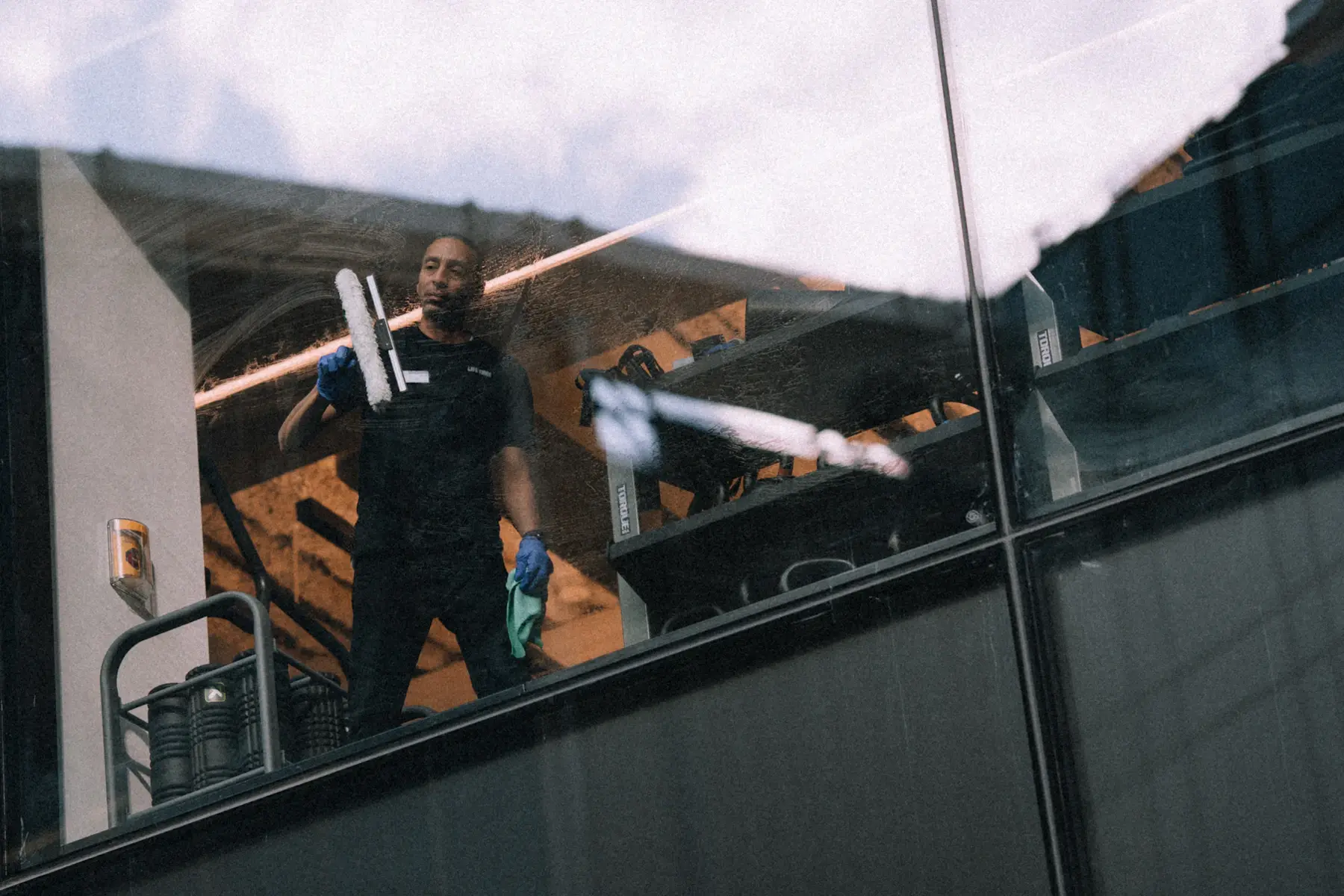 An installer working a squeegee across a full-height pane of glass from the inside